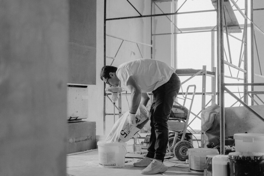 A Man in a White T-shirt and Black Pants Holding a Plastic Bag